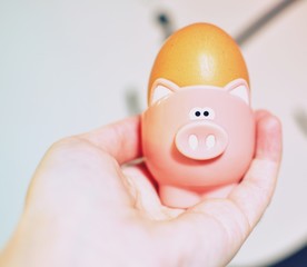 Boiled egg in a pink piggy stand held in a white woman hand.