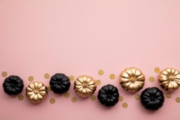 Gold and black pumpkins on pastel pink. Flat lay thanksgiving composition