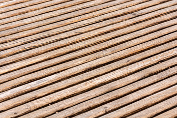 Thin brown wooden slats background. Parallel lines. Blurred background. Cracks and scuffs on the boards.