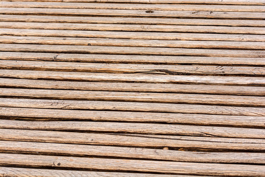 Thin brown wooden slats background. Parallel lines. Blurred background. Cracks and scuffs on the boards.