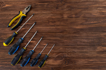 Work tool of the wizard. Screwdrivers, pliers, wire cutters on a wooden surface. Free space for text.