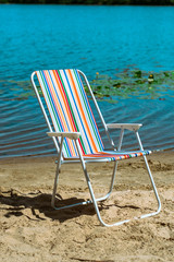 Multi-colored chair on the beach. Multi-colored striped chair on the beach sand