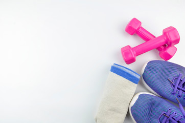 Fitness concept background with sneakers, dumbbells and towel. Top view with space for your text.