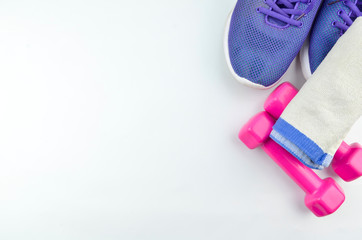Fitness concept background with sneakers, dumbbells and towel. Top view with space for your text.
