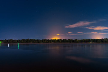 Bright orange glow over the island at night. River in the night