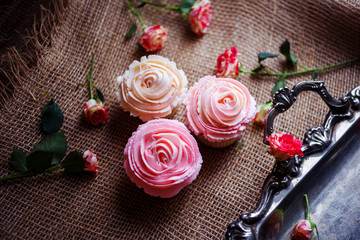 Beautiful creamy cupcakes on the silver tea tray decorated with roses 