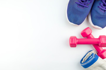 Fitness concept background with sneakers, dumbbells and towel. Top view with space for your text.