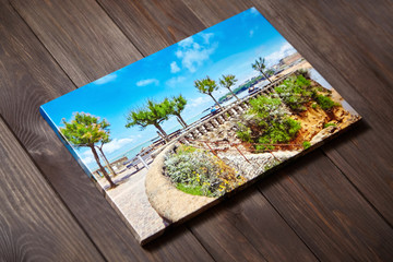 Canvas photo print on brown wooden background. Sample of gallery wrapping method. Colorful...