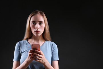 Portrait of beautiful young woman with depressed facial expression standing in the dark holding her...
