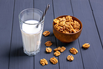 Natural walnut vegetable milk in glass cup and peeled nuts in a wooden bowl on dark gray background Nutritious and tasty drink. Alternative to cow's milk. Top view Flat lay Lactose free concept