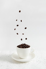 Aromatic coffee beans in a white cup, levitation on white background.
