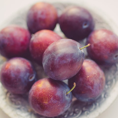 Ripe purple plums in a silver plate closeup.