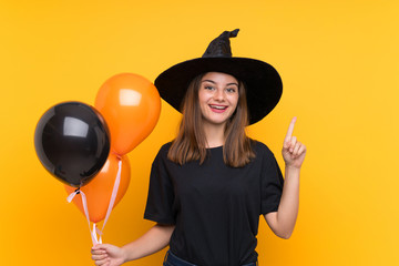 Young witch holding black and orange air balloons for halloween parties pointing up a great idea