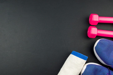 Fitness concept background with sneakers, dumbbells and towel. Top view with space for your text.