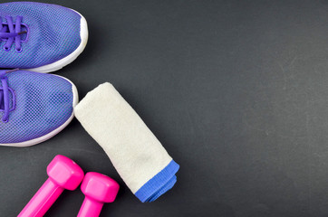 Fitness concept background with sneakers, dumbbells and towel. Top view with space for your text.
