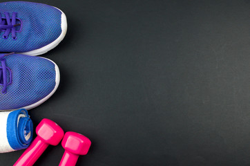 Fitness concept background with sneakers, dumbbells and towel. Top view with space for your text.