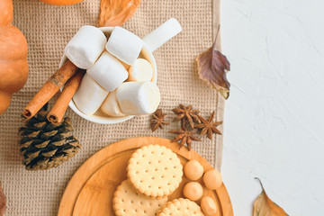 Pumpkin With Cups Of Coffee. Autumn still life from pumpkin, pine cones, mug of cocoa, coffee or hot chocolate with marshmallow on warm plaid with garland. Concept of cozy winter home environment
