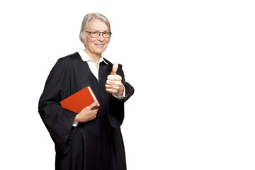 Best legal advice concept: mature woman in a black gown with a law book making the thumb's up sign.