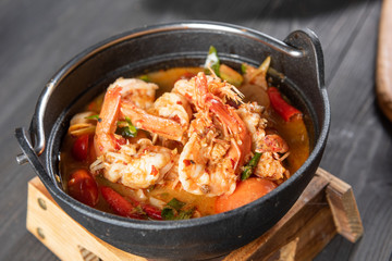 Chilli Soup with Shrimp or Tom Yum Kung is a popular Thai food and has a worldwide reputation, there is a hot and spicy taste of Thai identity and many ingredients with herb and serve in black bowl.