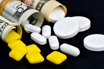 Dollar rolled up with pills flowing out isolated on black background, high costs of expensive medication concept. Copy space - image