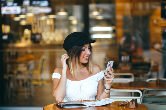 Chica en cafetería con el móvil