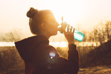 Young woman drinks from a shaker in the sun on nature