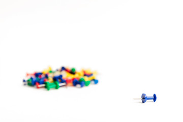 pushpin lies separately from the rest of the heap of the same buttons on a white background