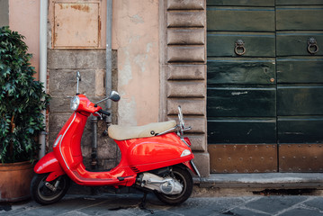 un scooter rouge devant une porte verte. Un scooter en Italie. Un vespa dans une rue.