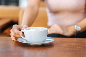 Young woman sitting and holding cup of coffee in a cafe