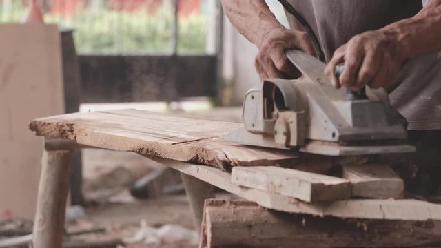 Slow motion of craftsman use polishing machine to make splat is smooth and the machine split some pieces of wood in workplace during day time.