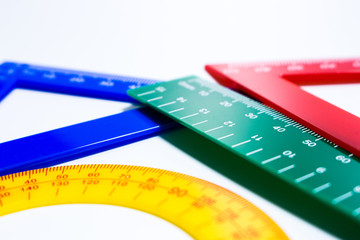 Close up of colourful rulers and protractor in white background