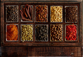 Assortment of peppercorns in a rustic wooden box.