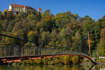chain bridge in autumn below a castle