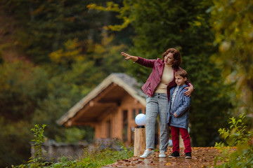 Travelers mother and son on a walk in the autumn mountains against the background of a wooden house...