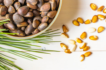 Cedar cone, nuts and a branch of Siberian cedar on a light wooden background. The concept of...