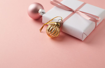Christmas baubles and Christmas present. Bright paper background. Close up. Copy space. 