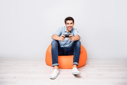 Full length body size photo of trendy man addicted to playing video games wearing white sneakers holding joy stick with hands isolated over grey color background