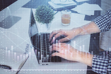 Double exposure of graph with man typing on computer in office on background. Concept of hard work.