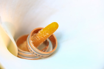 Macro close up of two wedding rings on yellow brawl of white flower