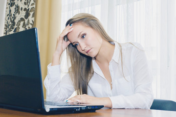 Headache in the workplace from restarting work. Stress at work. The girl holds her head from fatigue and headache.