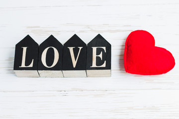 Red heart and wooden figures with the inscription love on a white wooden background. Valentine's day concept. Romantic message