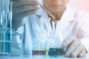 Scientist testing some chemical sample at laboratory with lab glassware on the table. Science research and development new innovation technology concept.
