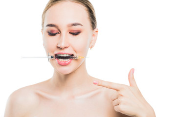 Young girl holding a syringe with filler for lip augmentation in her teeth.