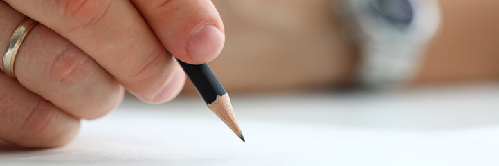 Male arm holding black simple pencil ready to draw