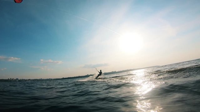 Athlete rides a kiteboard on water. Kite surfer kiteboarding.