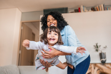 Mother playfully swinging her little daughter in the air