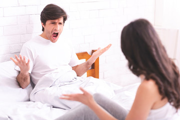 Obraz premium Emotional spouses screaming at each other in bed