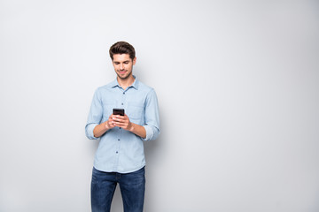 Portrait of charming focused man stand copyspace using cellphone type message to his online friends...