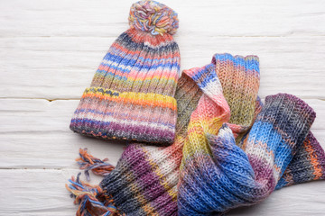 Closeup set of knitted winter cap and scarf on white wooden board