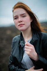 A young girl with long red hair and freckles looks at the camera.